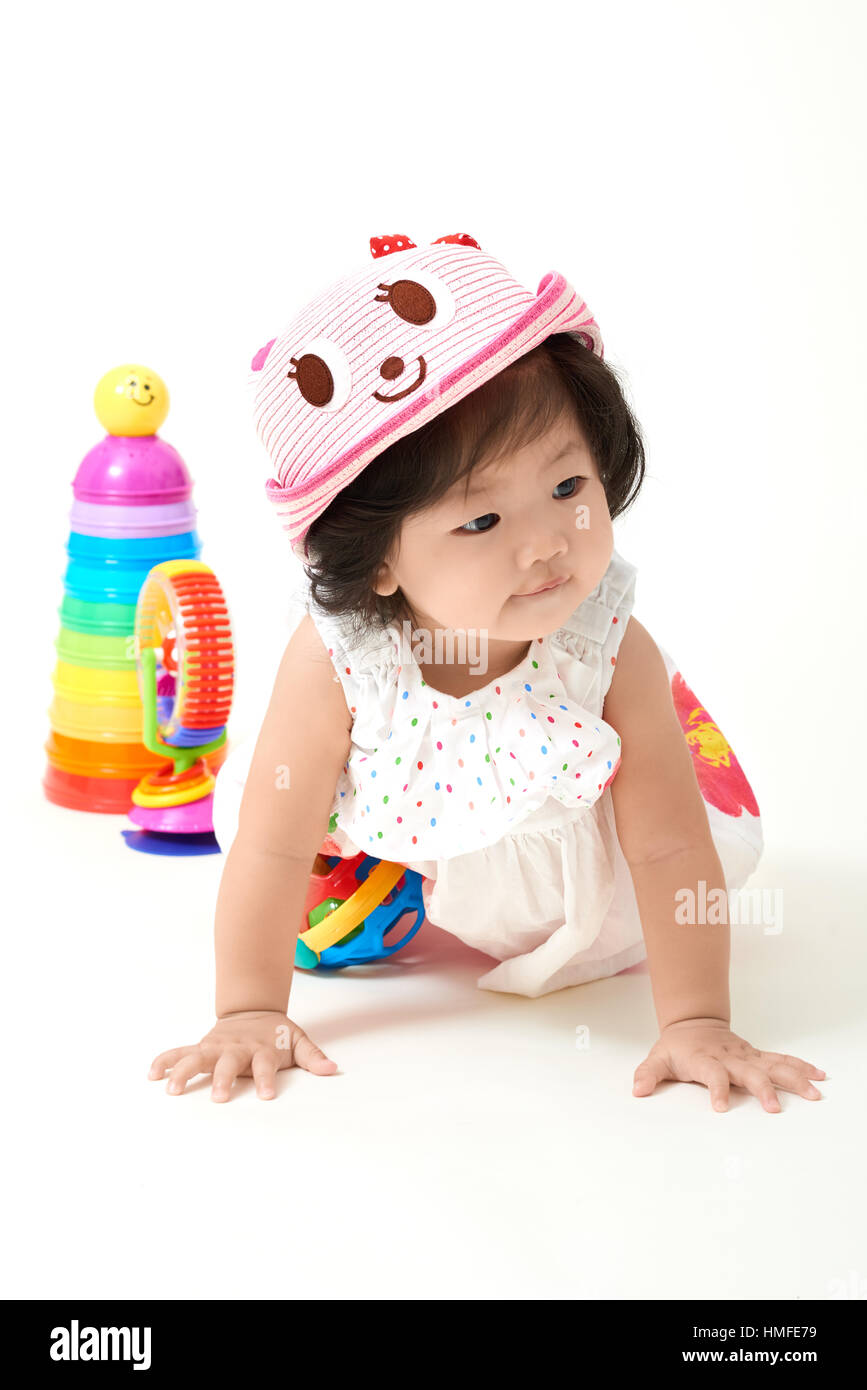 Asian baby girl wearing colorful outfit playing with toys. Stock Photo