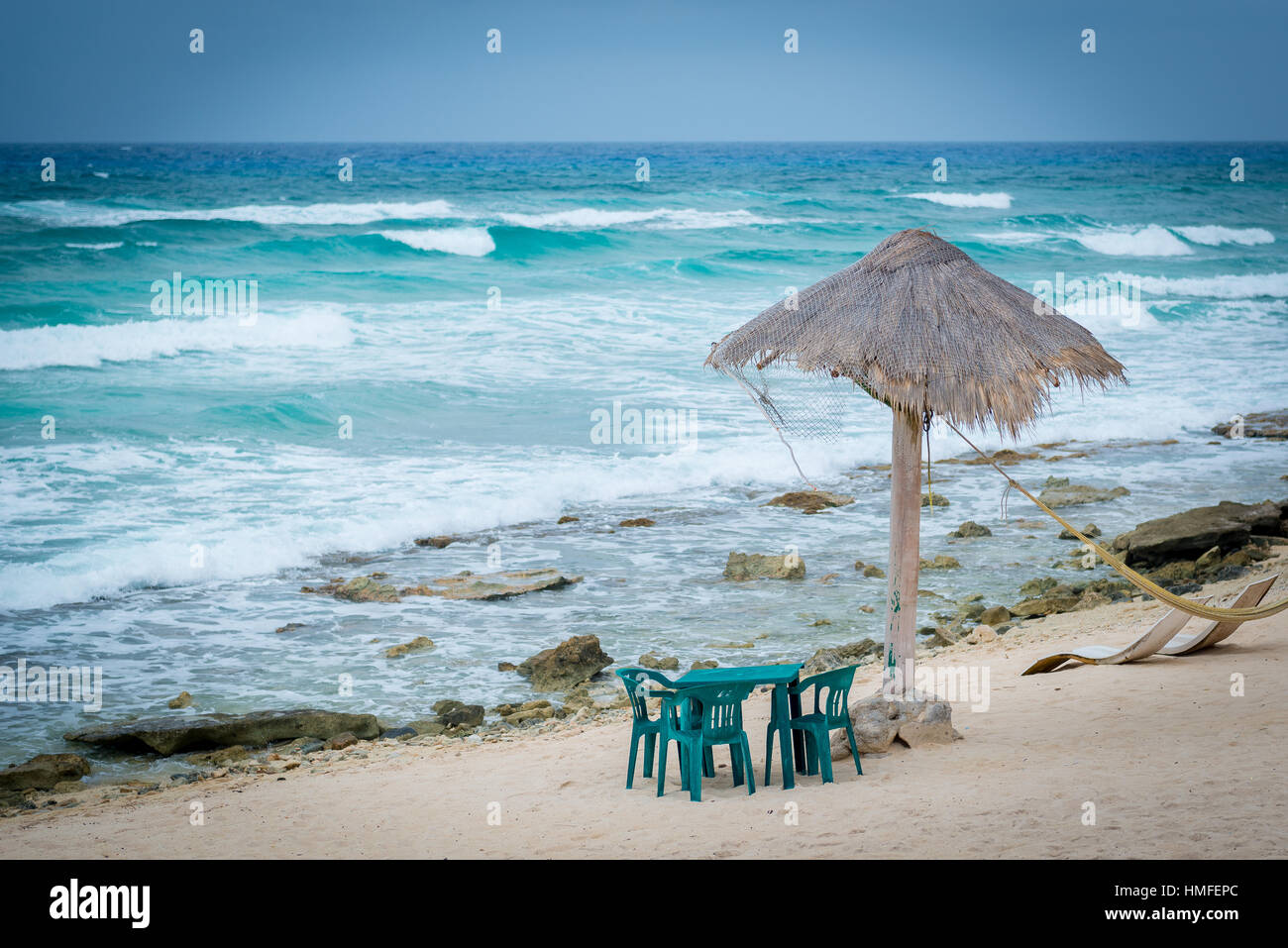 Table set on beach with grass umbrella shade Stock Photo - Alamy