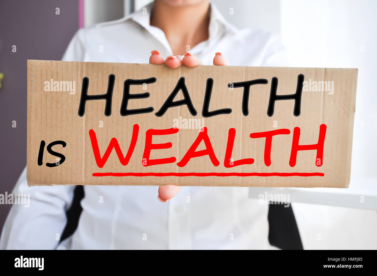 Health is wealth saying written on a cardboard sign held by a woman Stock Photo