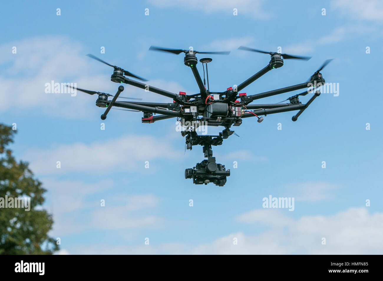 A camera drone in flight against a blue sky Stock Photo