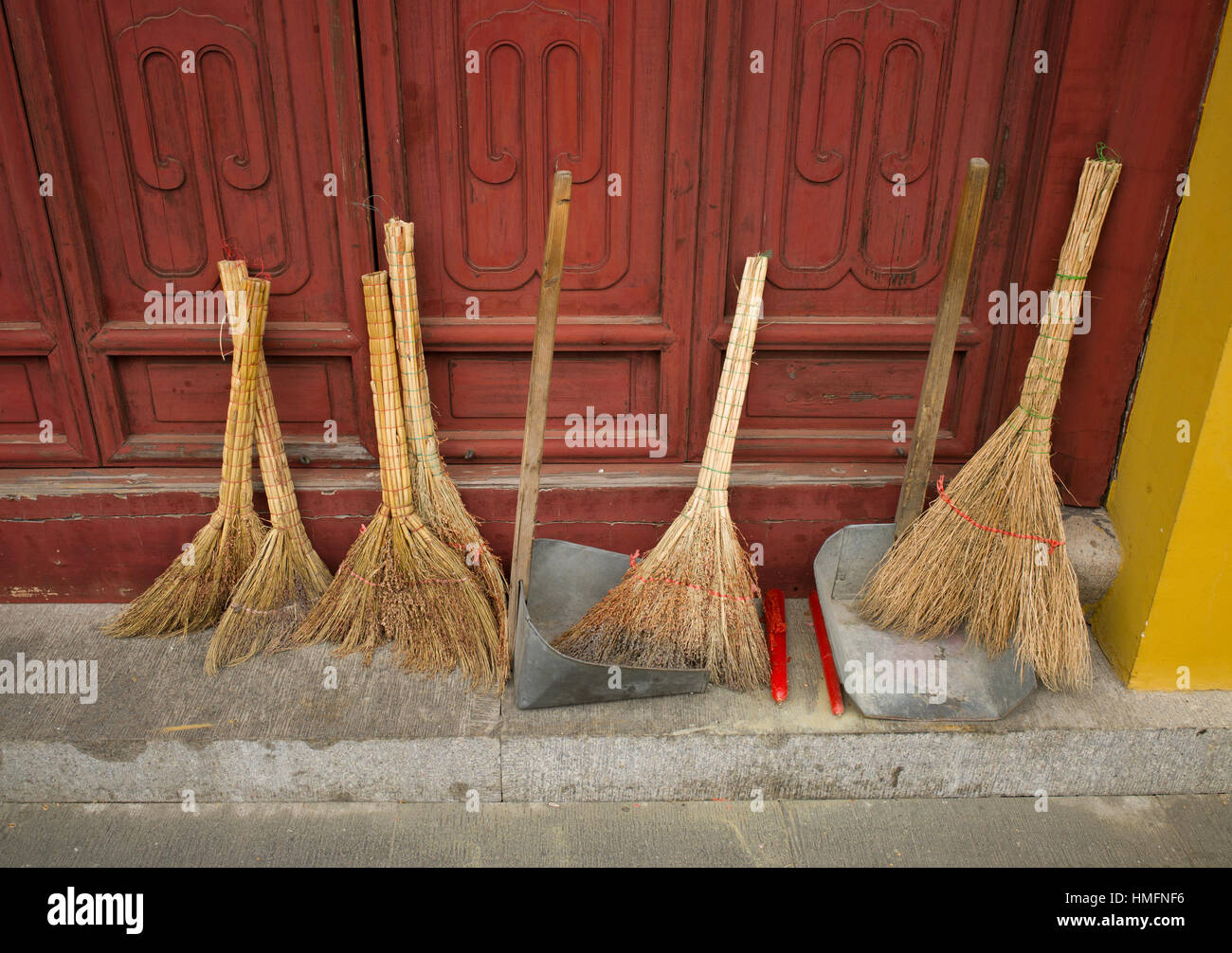 Dustpans and brushes propped against temple door, Suzhou, China Stock