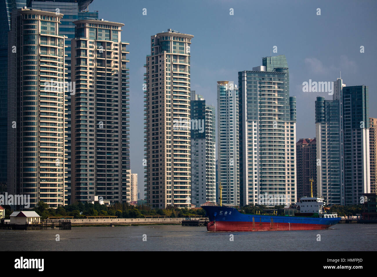 A barge carrying goods slides infant of group of Shanghai apartment buildings housing thousands of residents, Pudong River, Shanghai Stock Photo