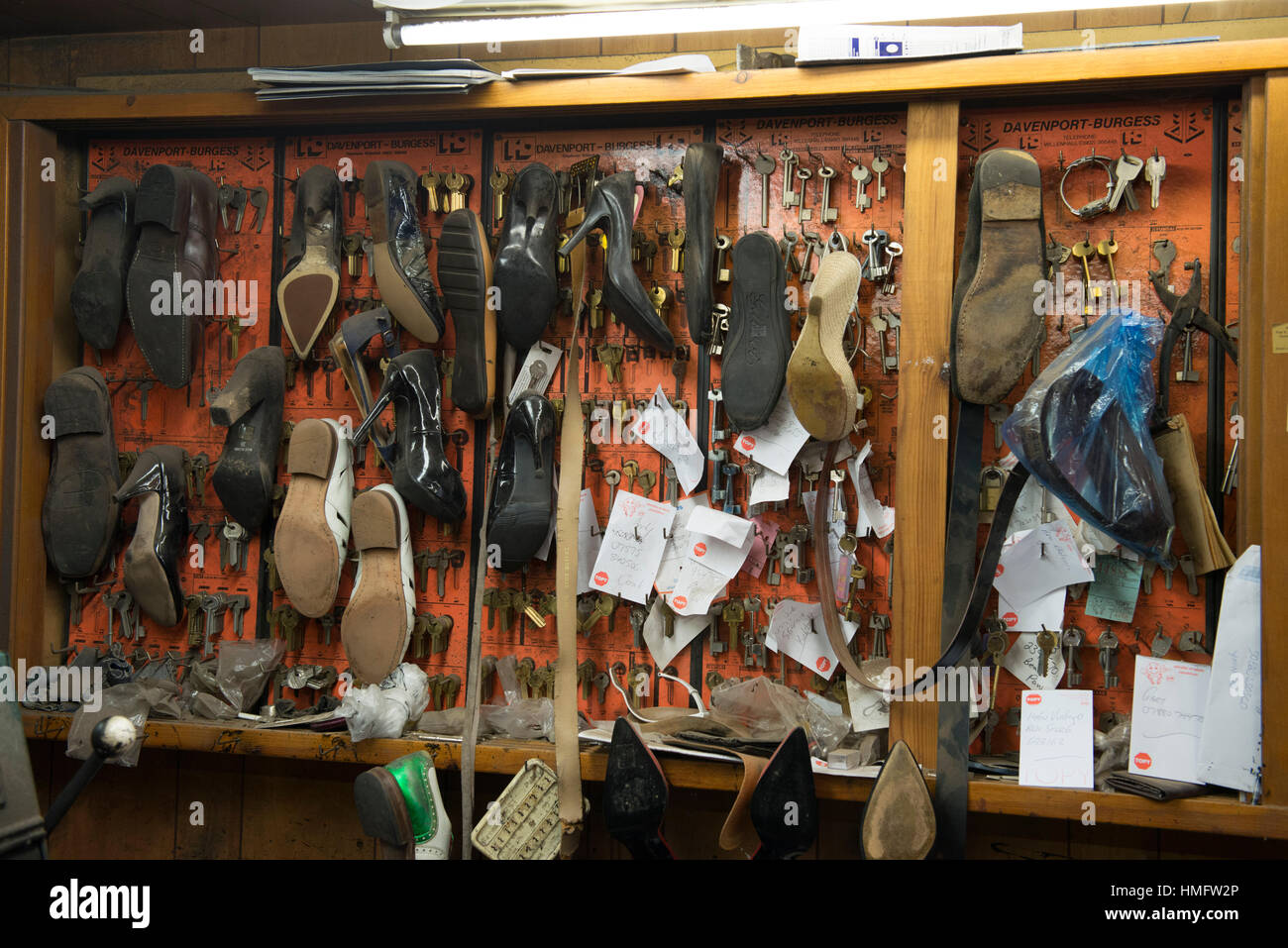 an old fashioned shoe repair / cobbler fixes shoes in his busy shop
