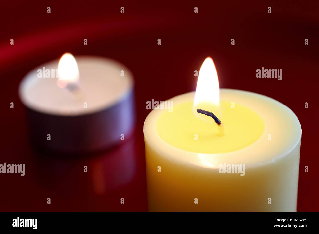 Flames of a burning wax candles isolated on a red background Stock