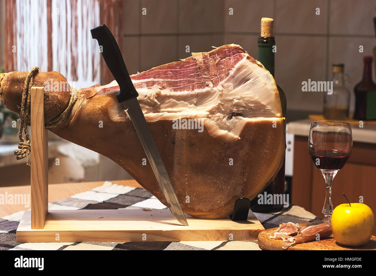 Spanish Jamon Serrano on wooden tabla jamonera with knife, apple, glass and  bottle of red wine. Home cooking, food photo concept Stock Photo - Alamy