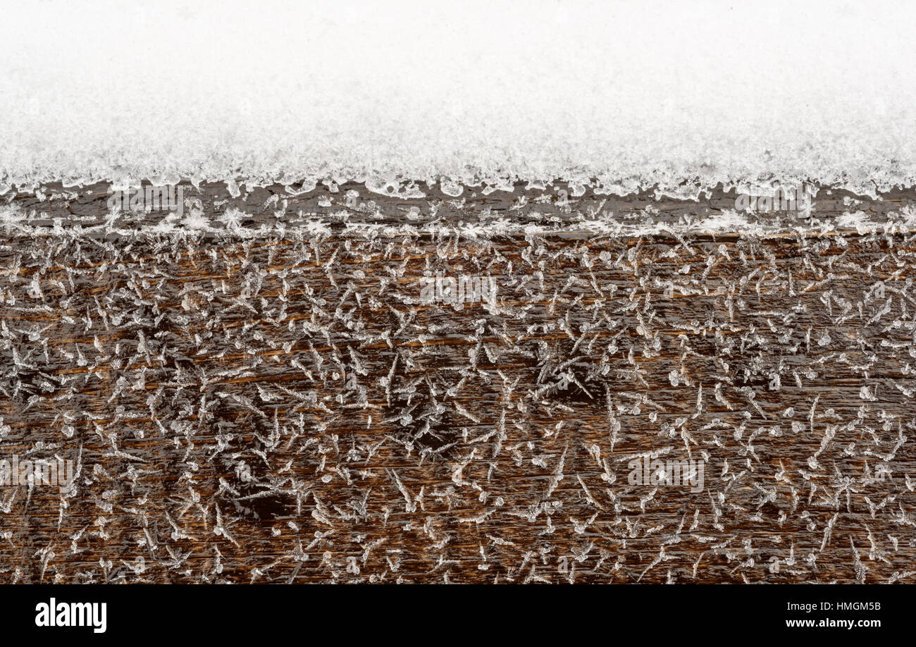 Frosted snowflakes and ice on natural brown wood. Copyspace area for