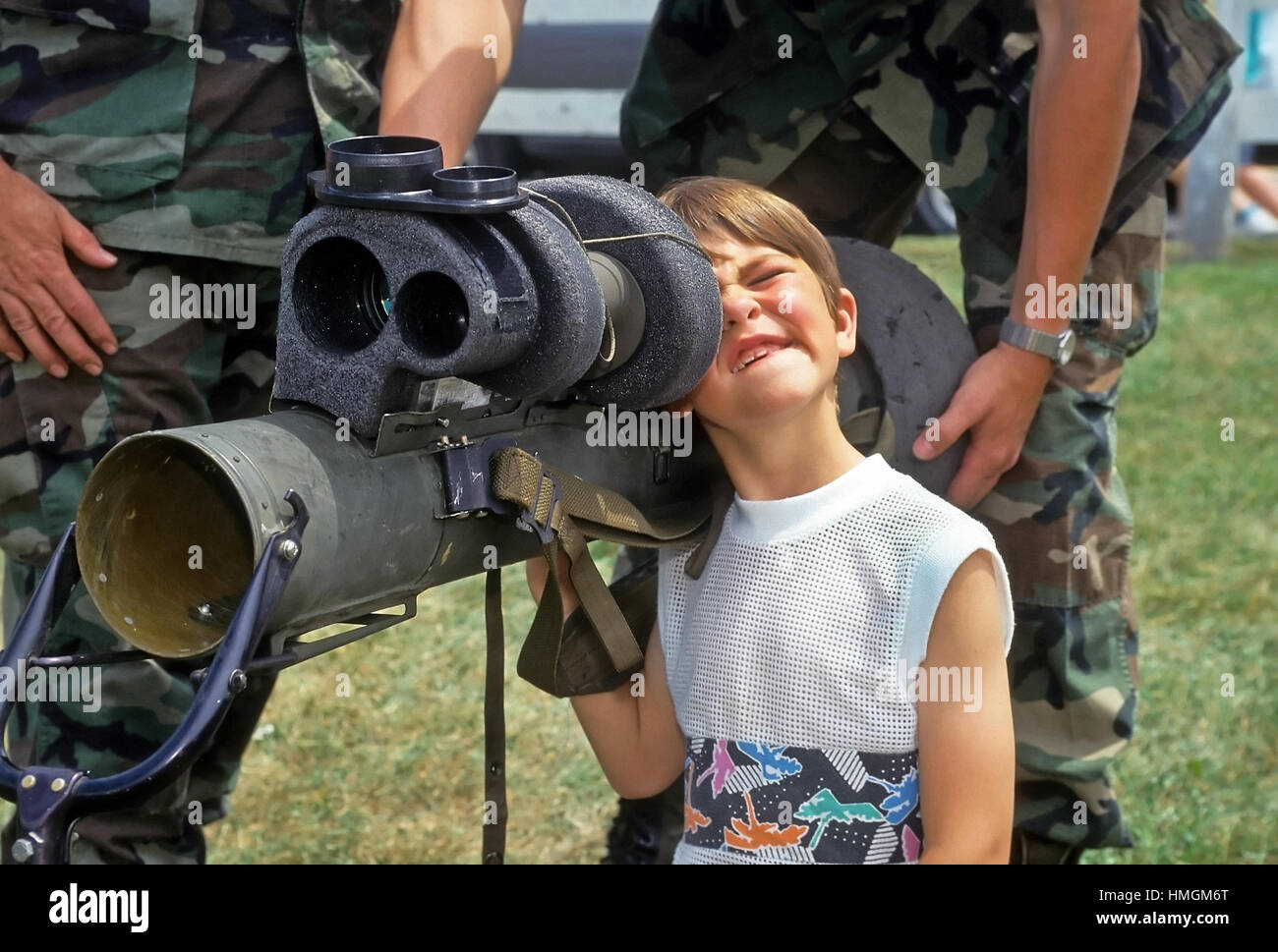 A five year old boy makes a funny face as he peeks through the sighting mechanism of a bazooka at a display put on by the National Guard in Plainfield Stock Photo