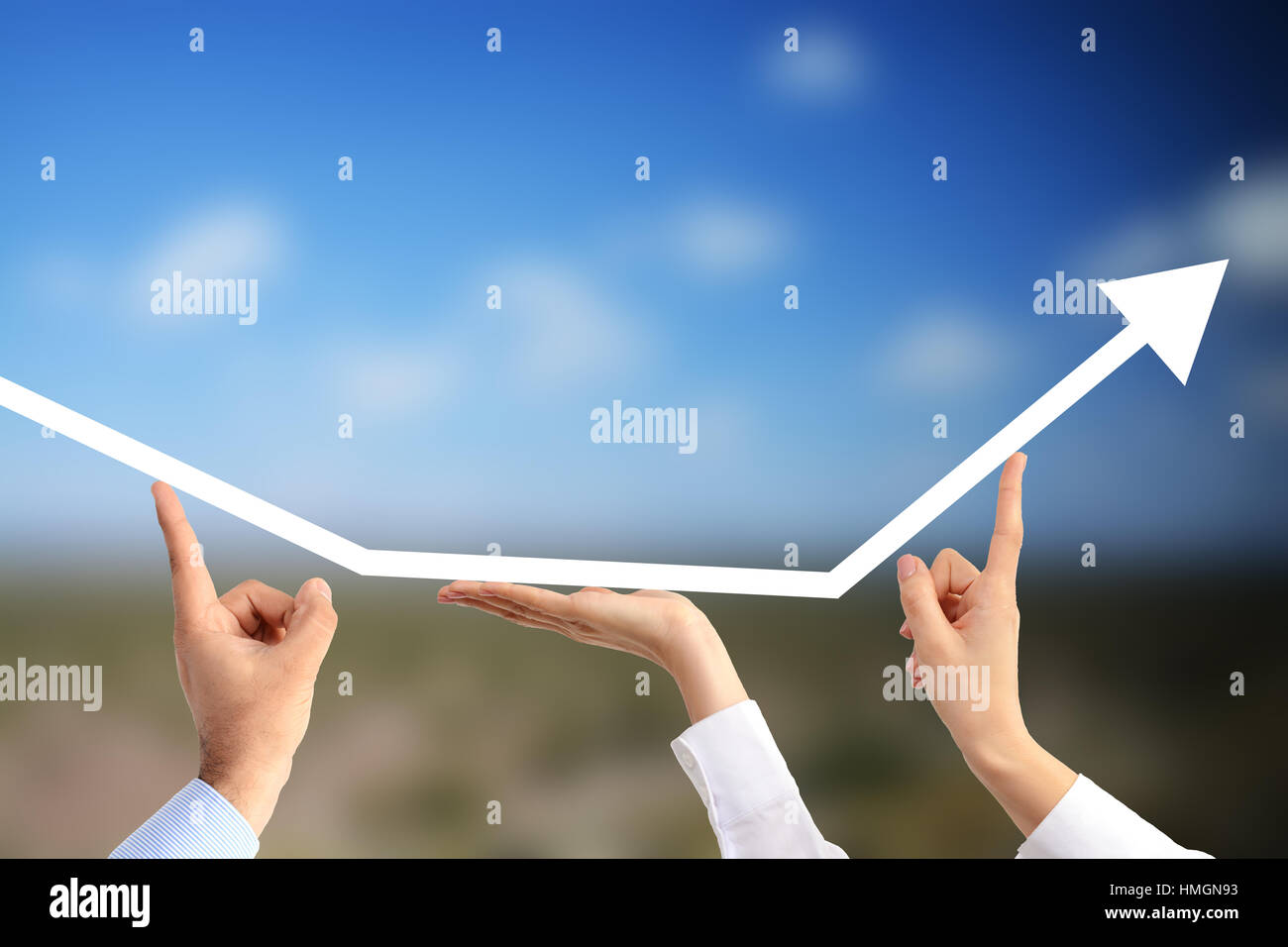 Business people’s hands holding an up going arrow suggesting the benefits of teamwork on an agricultural field background Stock Photo