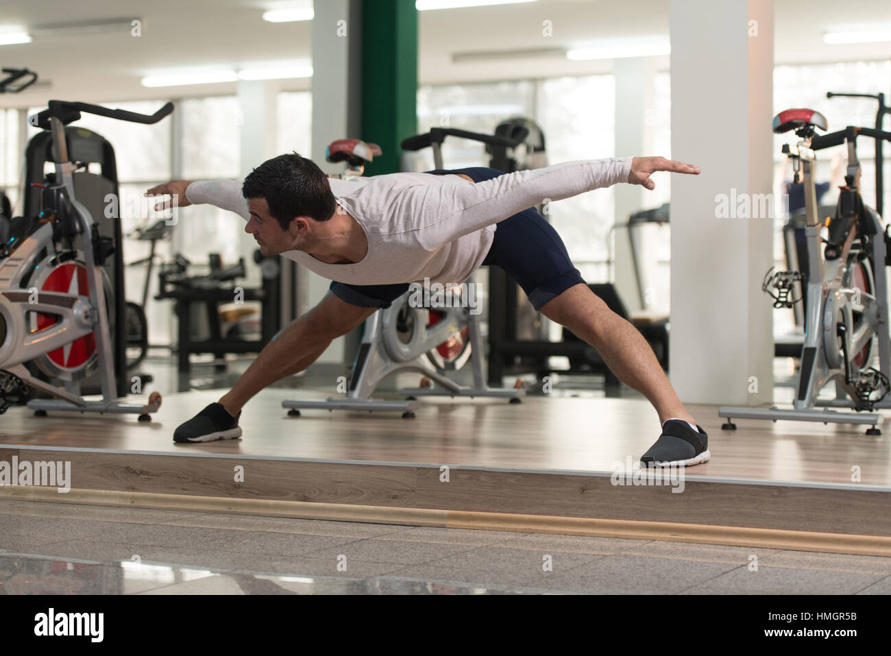 Muscular Man Stretches At The Floor In A Gym And Flexing Muscles ...