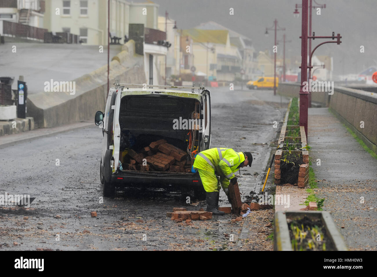 Seaton, Devon, UK.  3rd February 2017.  UK Weather.  A workman clearing up debris from a damage section of wall on the seafront at Seaton in Devon, after waves from the storm overtopped the sea wall during night.  Photo by Graham Hunt/Alamy Live News Stock Photo
