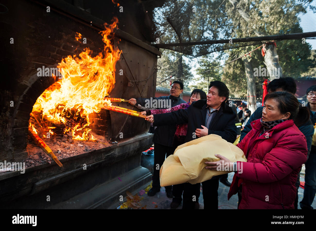 A group of worshippers light incense and throw joss paper into a furnace to celbrate the new year at a temple on Taishan mountain, China Stock Photo