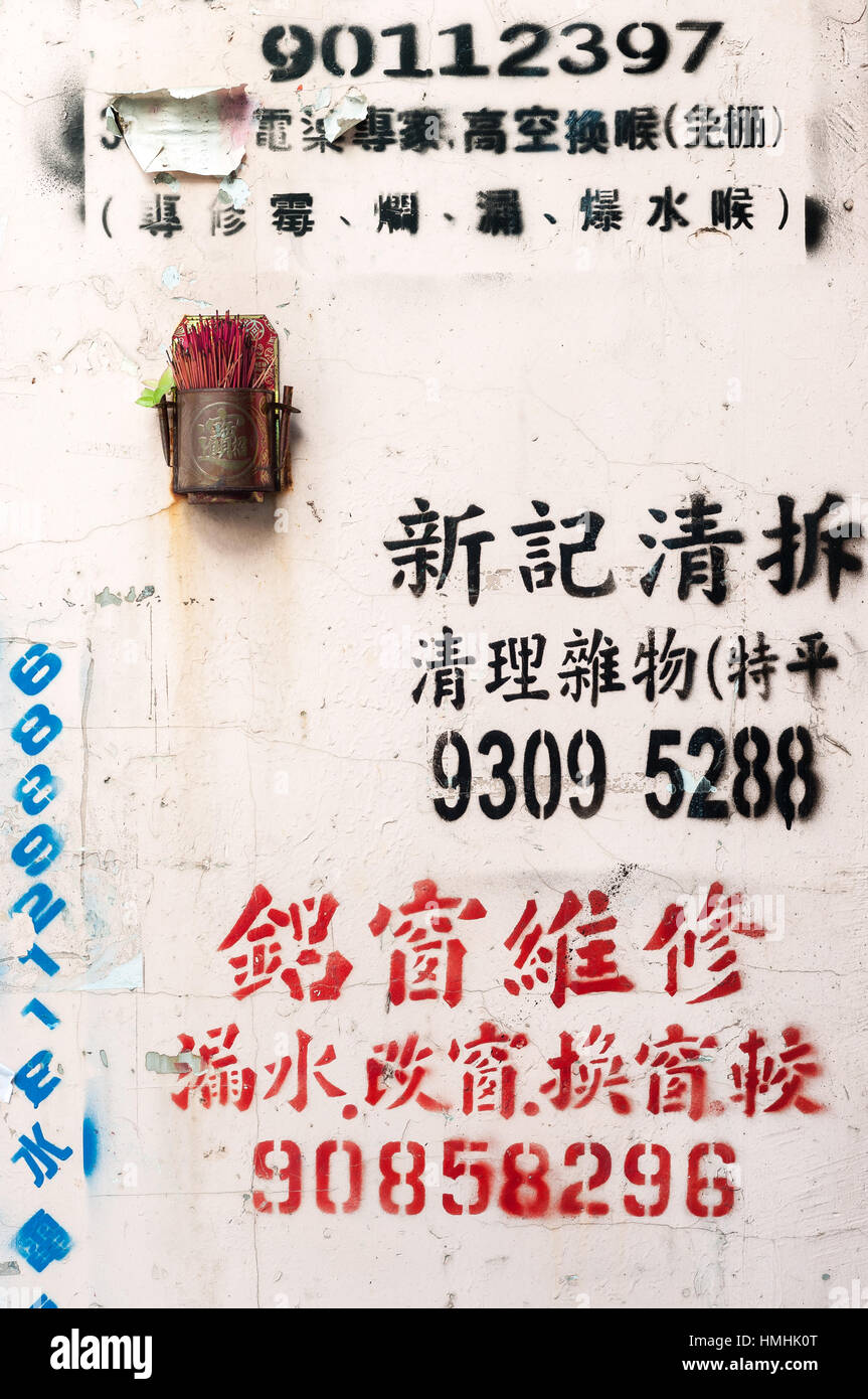 Small metal shrine on an advertisement-covered wall, Hong Kong Stock Photo