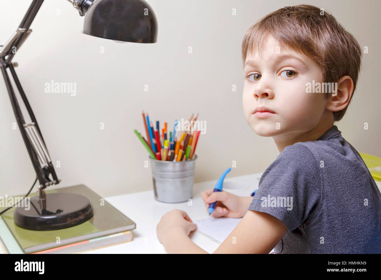 Boy sitting at the desk home and doing his homework. Child writting. School, children, education concept Stock Photo