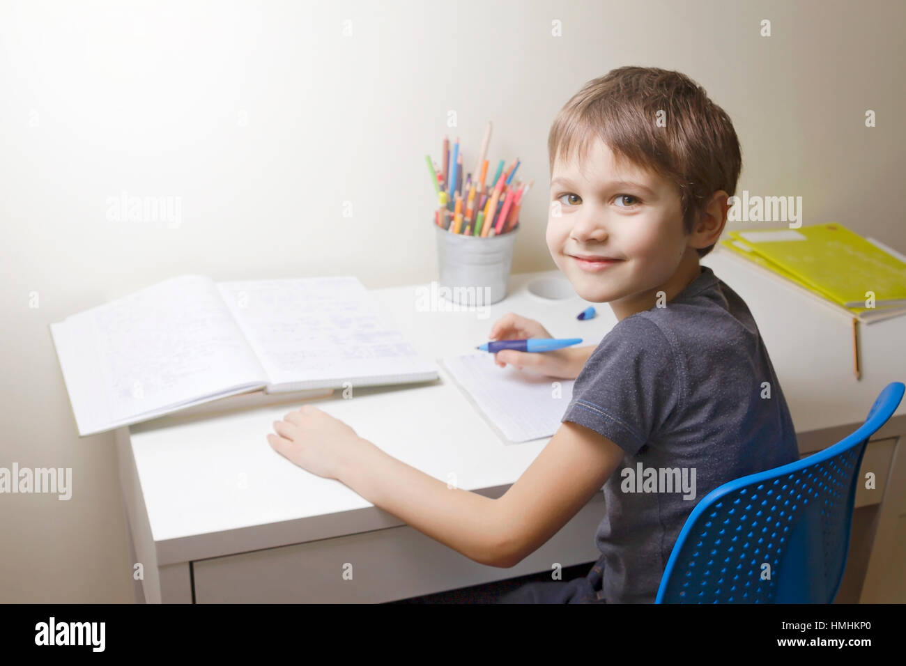 Happy little boy writting. Child sitting at the desk home and doing his homework. School, children, education concept Stock Photo