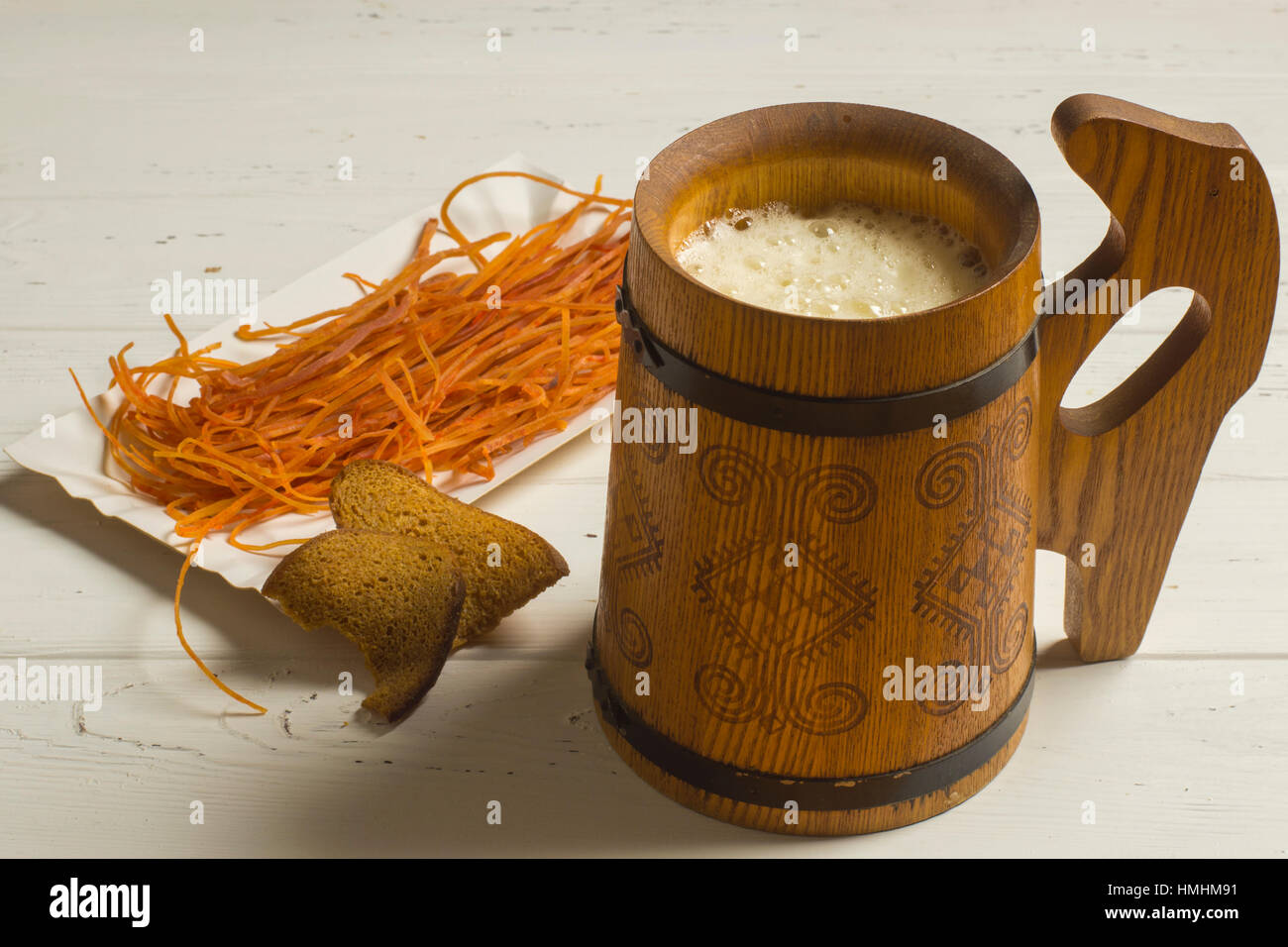 Mug of Beer, Dried Bread, and Dried Seafood on White Wooden Background Stock Photo