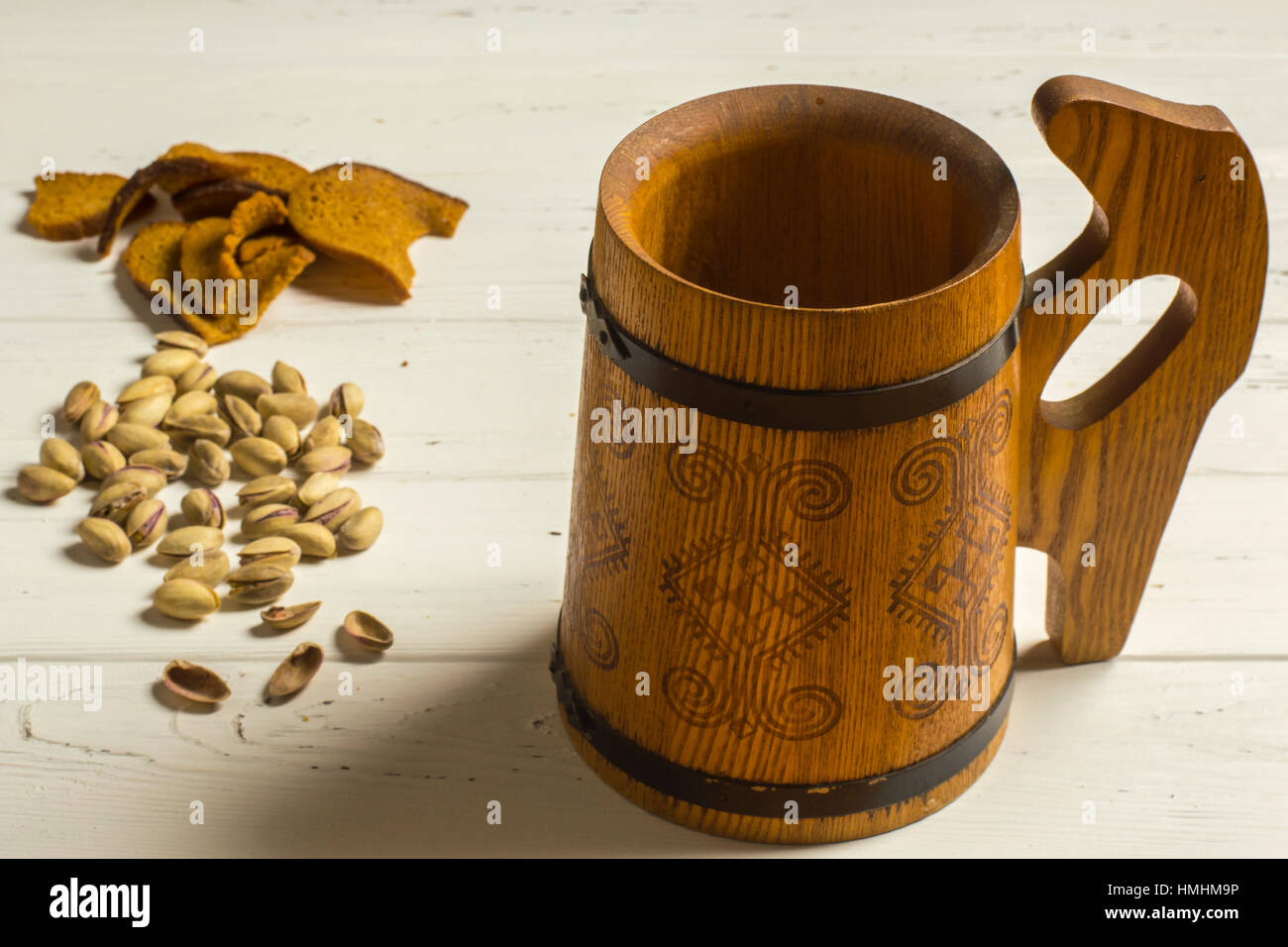 Wooden Beer Mug, Pistachio Nuts, and Dried Bread on Wooden Background Stock Photo