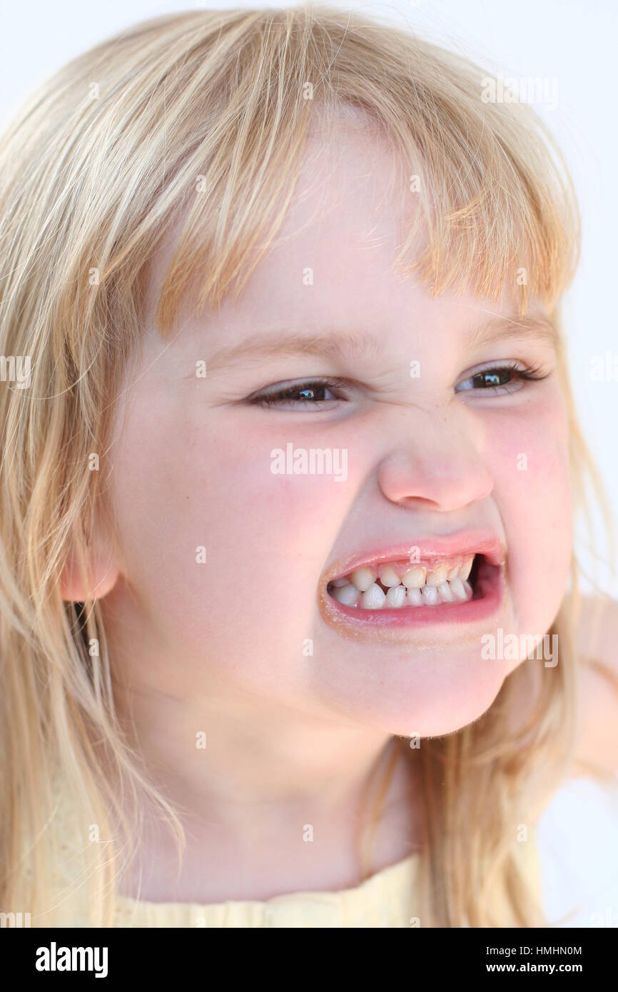 young blonde girl smiling / child kid making a funny face grinding teeth  looking very happy messing funny face Stock Photo - Alamy