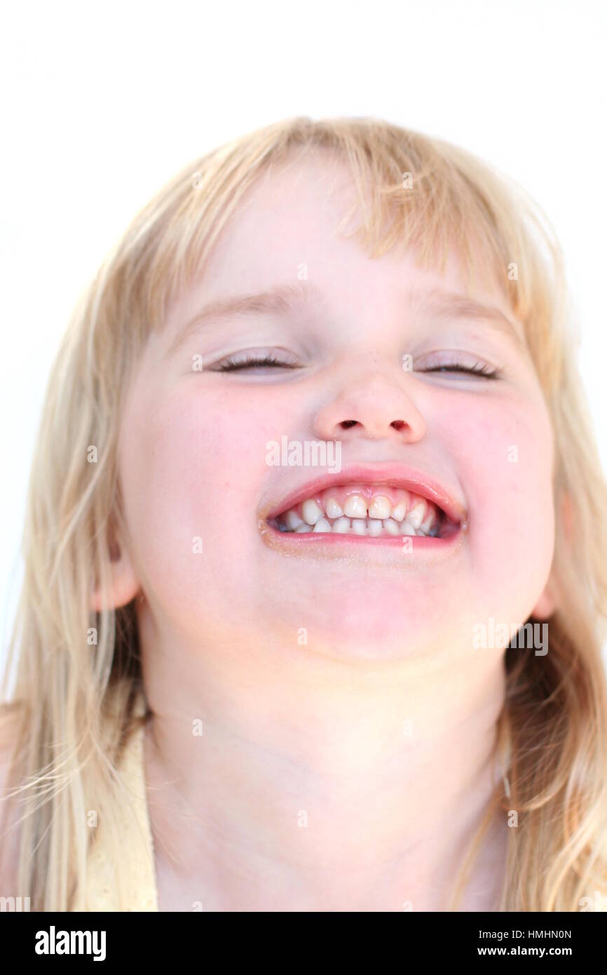 LIttle girl making a funny face, bursting with laughter with her eyes clothes, teeth clenched together, laugh out loud Stock Photo