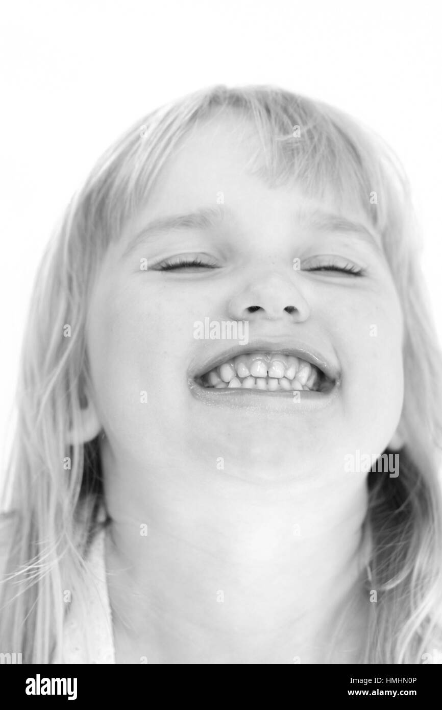 LIttle girl making a funny face, bursting with laughter with her eyes clothes, teeth clenched together pure joy happiness delight happy Stock Photo