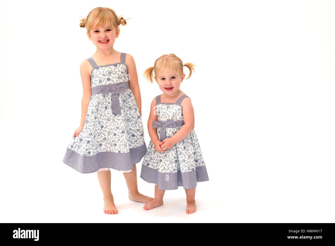 Little girls / sisters / children dressed in matching dresses with blonde pigtails in their hair Stock Photo