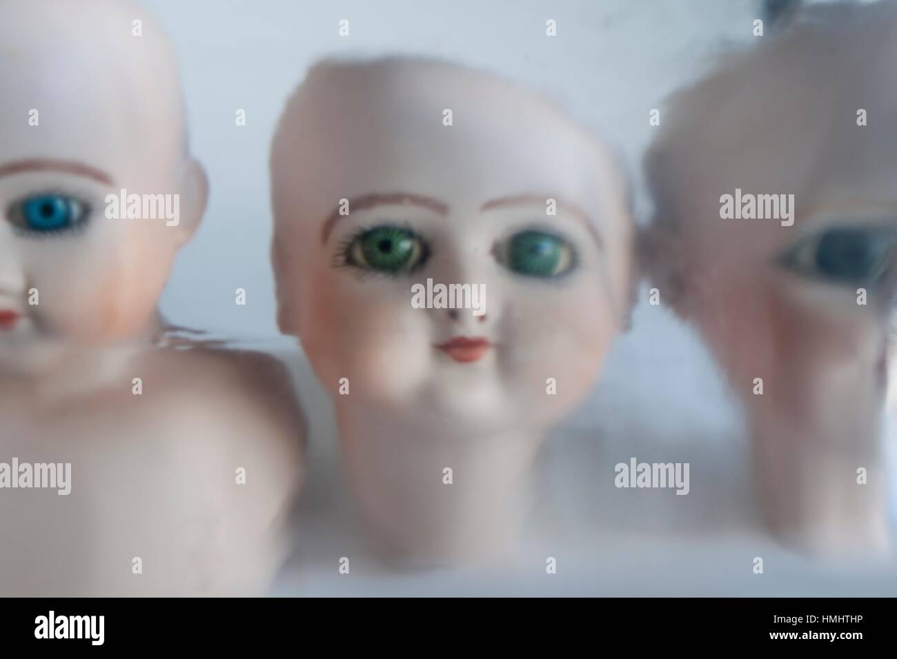 Primer plano de tres cabezas de muñecas de porcelana con ojos verdes,  mirando fijamente a la camara. , Close up of three porcelain doll heads  with Stock Photo - Alamy