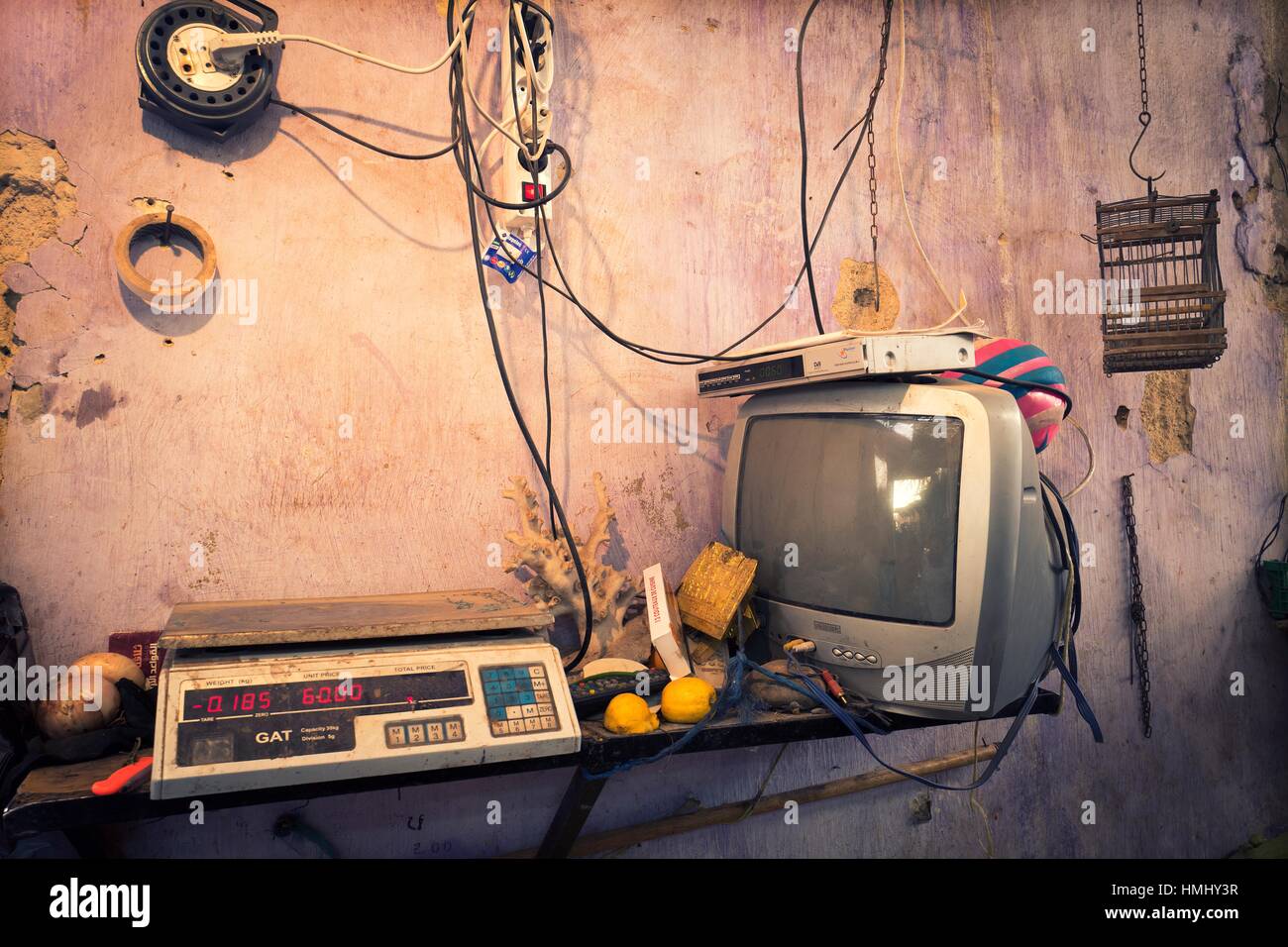 Inside a stall with wall, electric cables, plugs, television, scales
