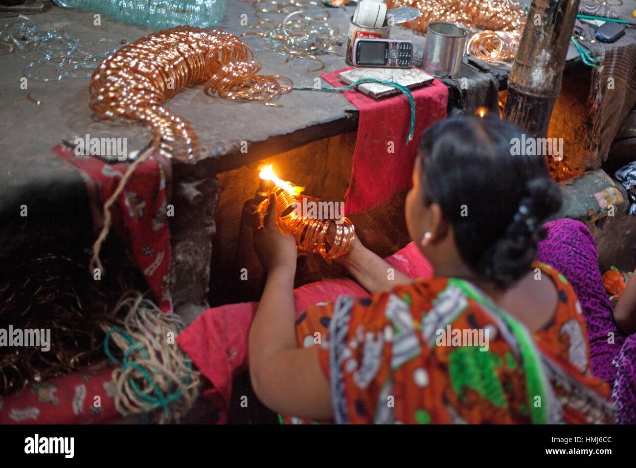 A Bangladeshi women working in front of small kilns at a glass bangle