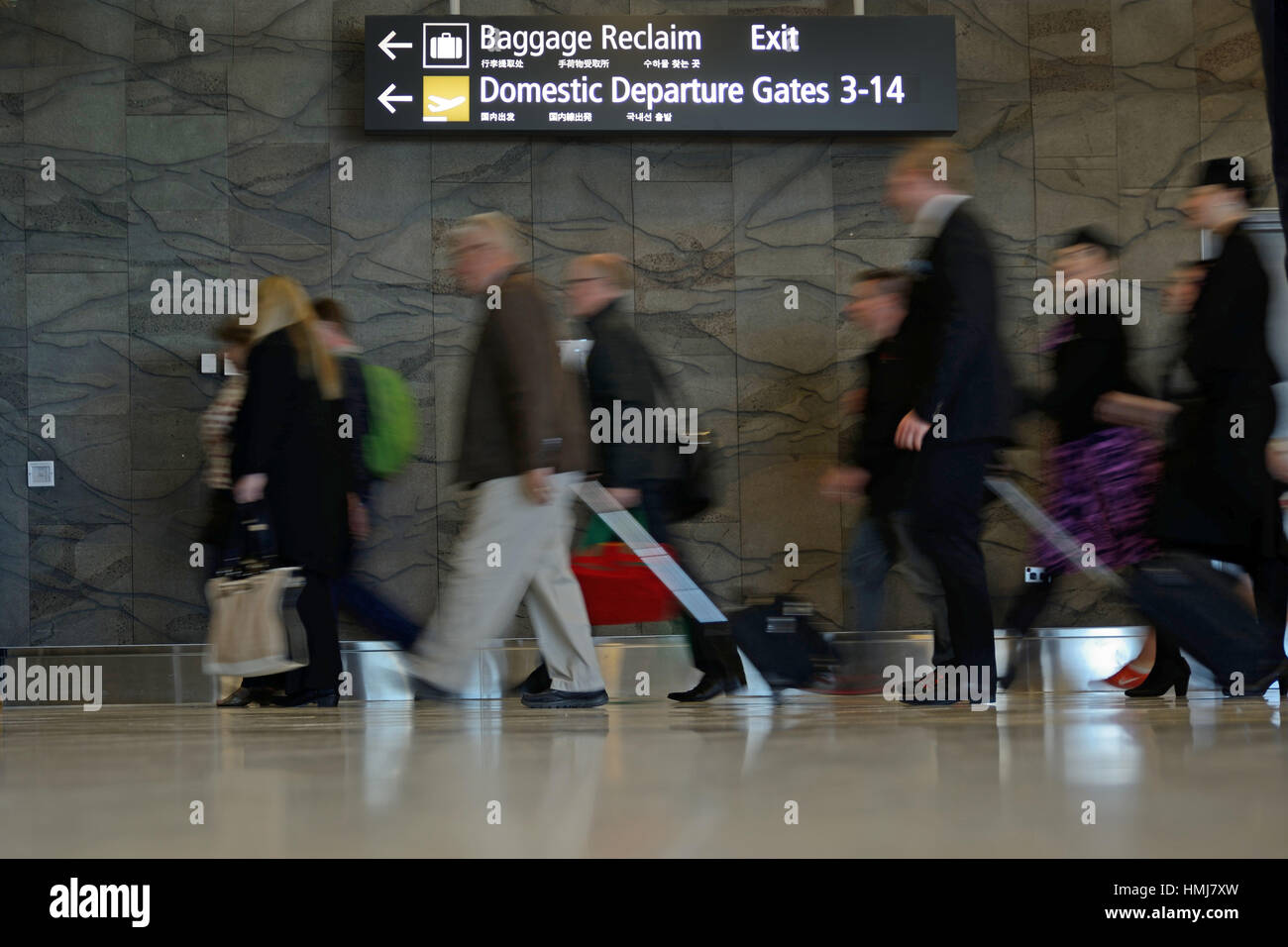 Passengers head for the domestic departures gate at an airport. Slow shutter speed for blurred motion. Stock Photo