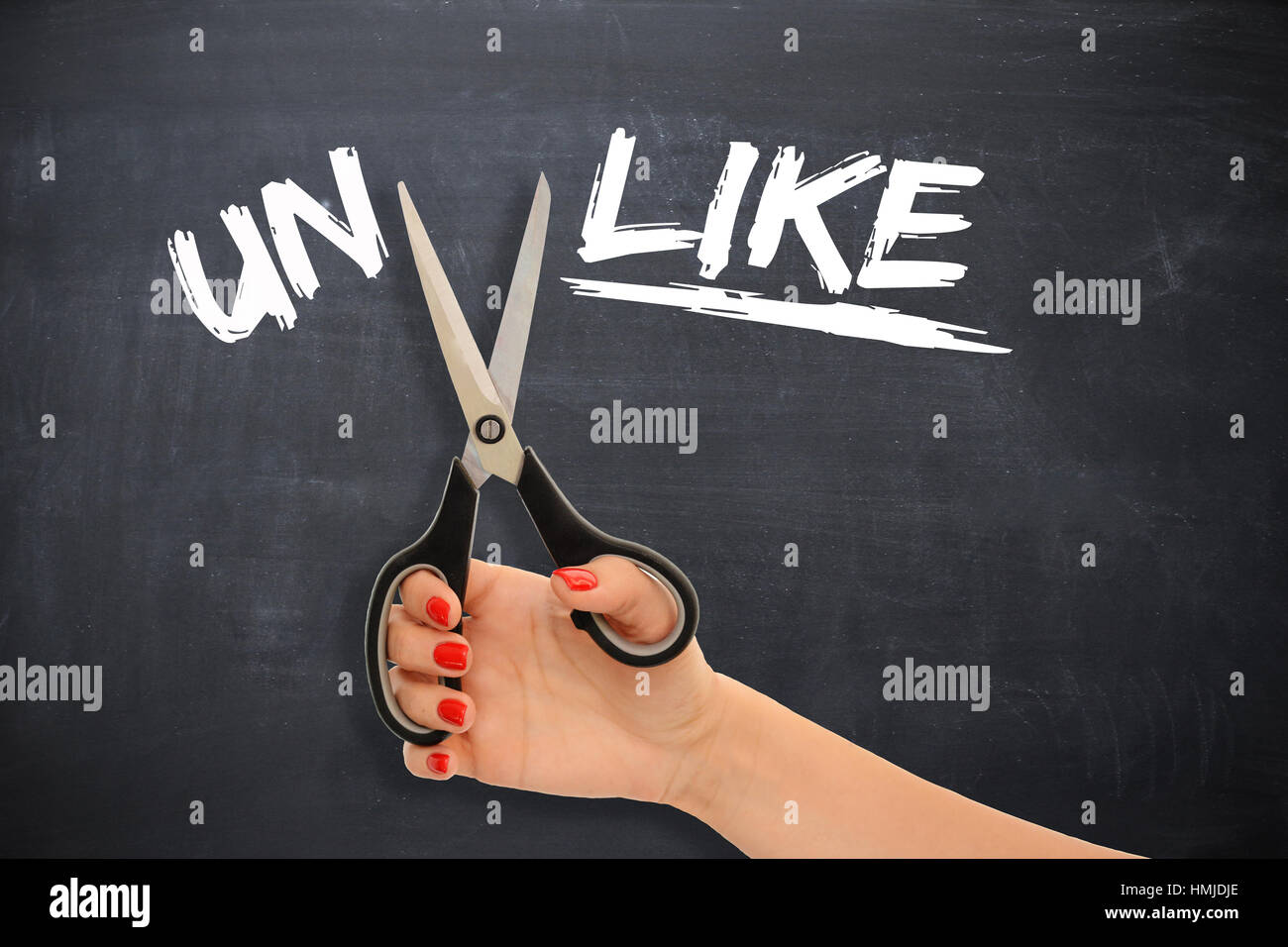 Woman transforming the word “unlike” to the word “like” by cutting the prefix with scissors Stock Photo