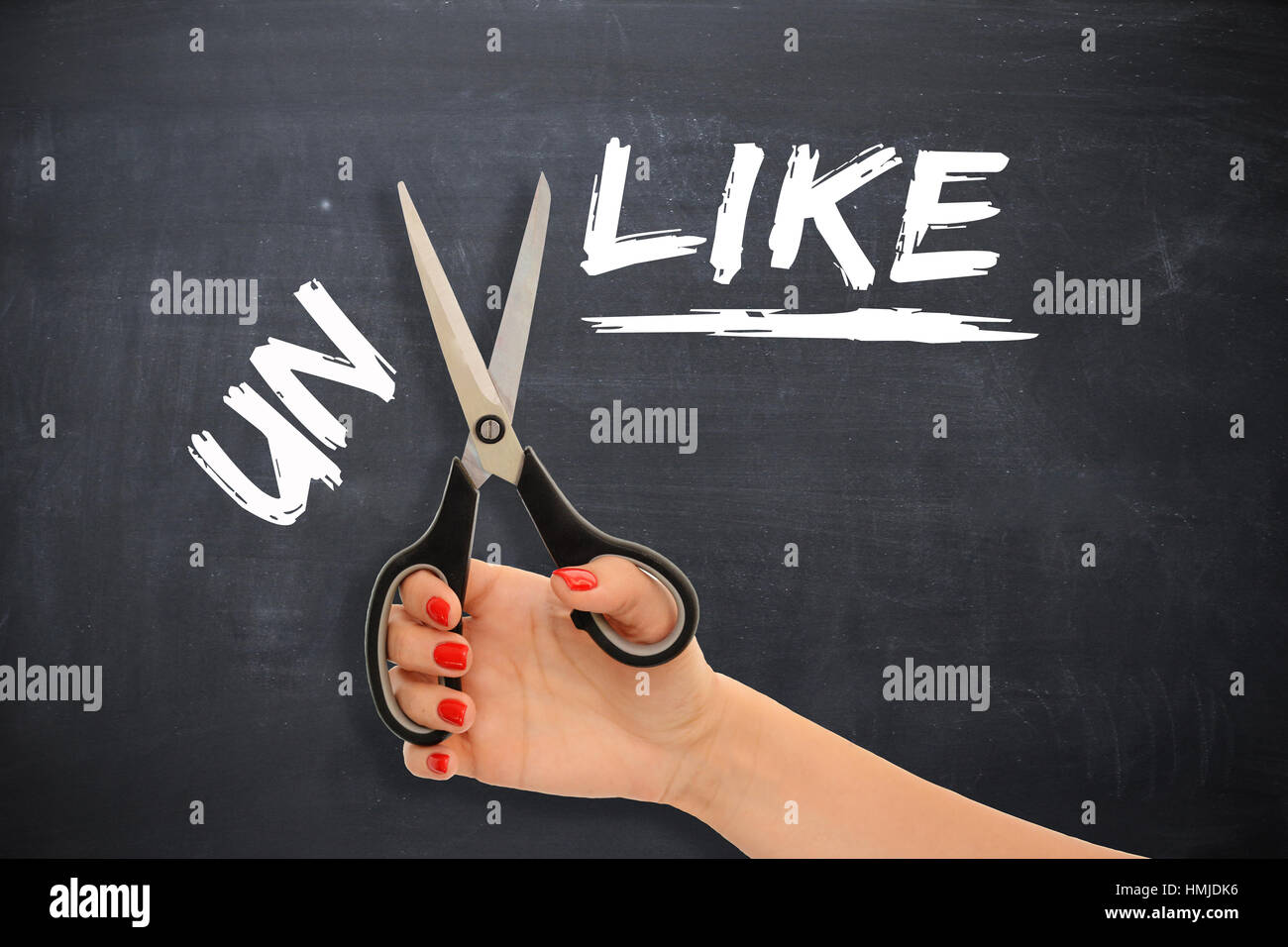 Woman transforming the word “unlike” to the word “like” by cutting the prefix with scissors Stock Photo