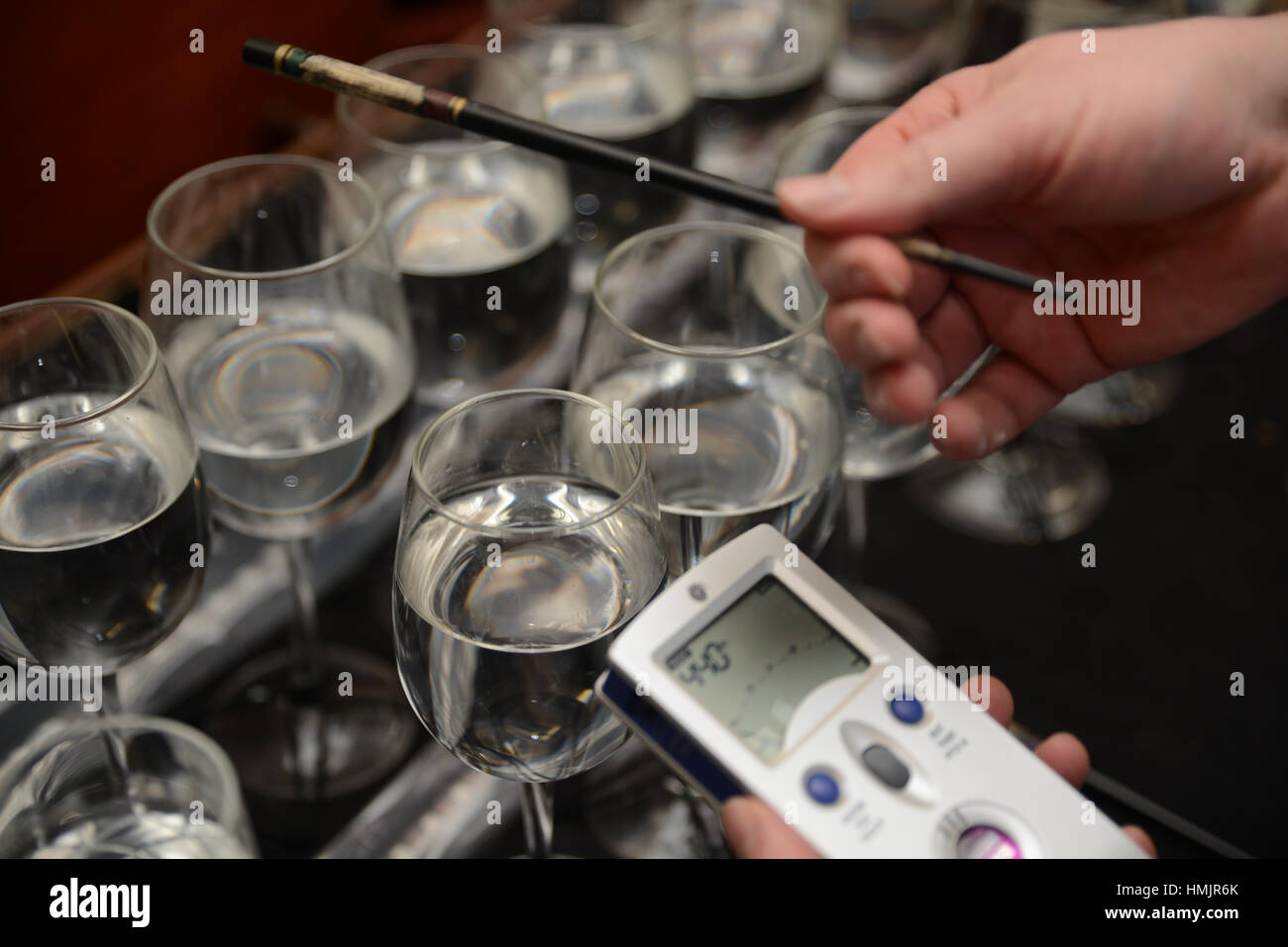 A musician tunes a set of wine glasses partly filled with water to make a full range of notes for a concert performance Stock Photo