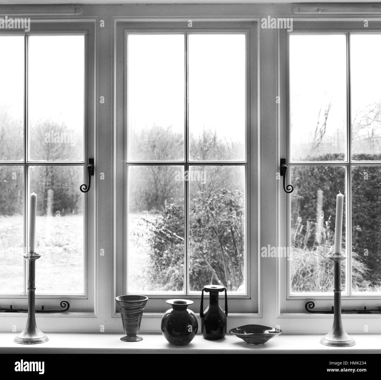 white window frame, with window sill with 2 candles and glass ornaments on white window sill