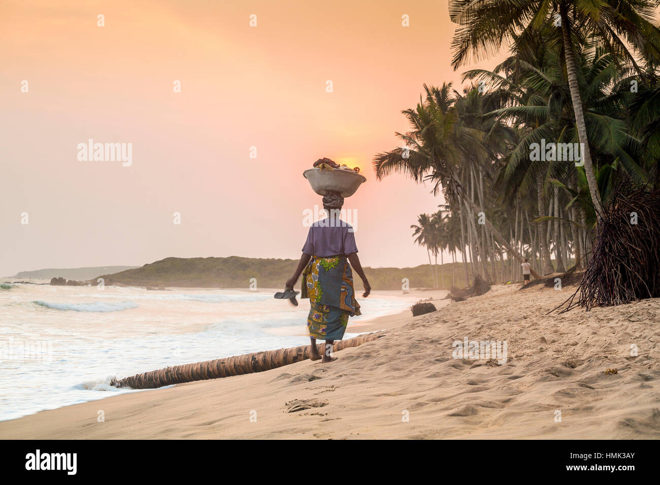 Local woman carrying goods on her head, beach, sunset, Volta River, Ghana Stock Photo
