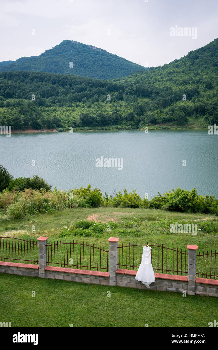 Wedding bridal dress is hanging outside. Lake view. Landscape Bulgaria Stock Photo