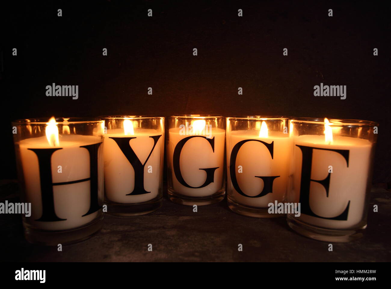 Candles in an English home at winter depict 'hygge', the Danish philosophy of embracing a contented, cosy and happy life.  Slate backdrop for  copy. Stock Photo
