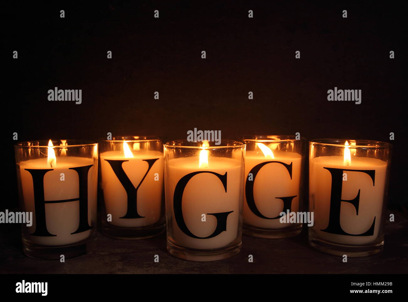 Candles in an English home at winter depict 'hygge', the Danish philosophy of embracing a contented, cosy and happy life.  Slate backdrop for  copy. Stock Photo