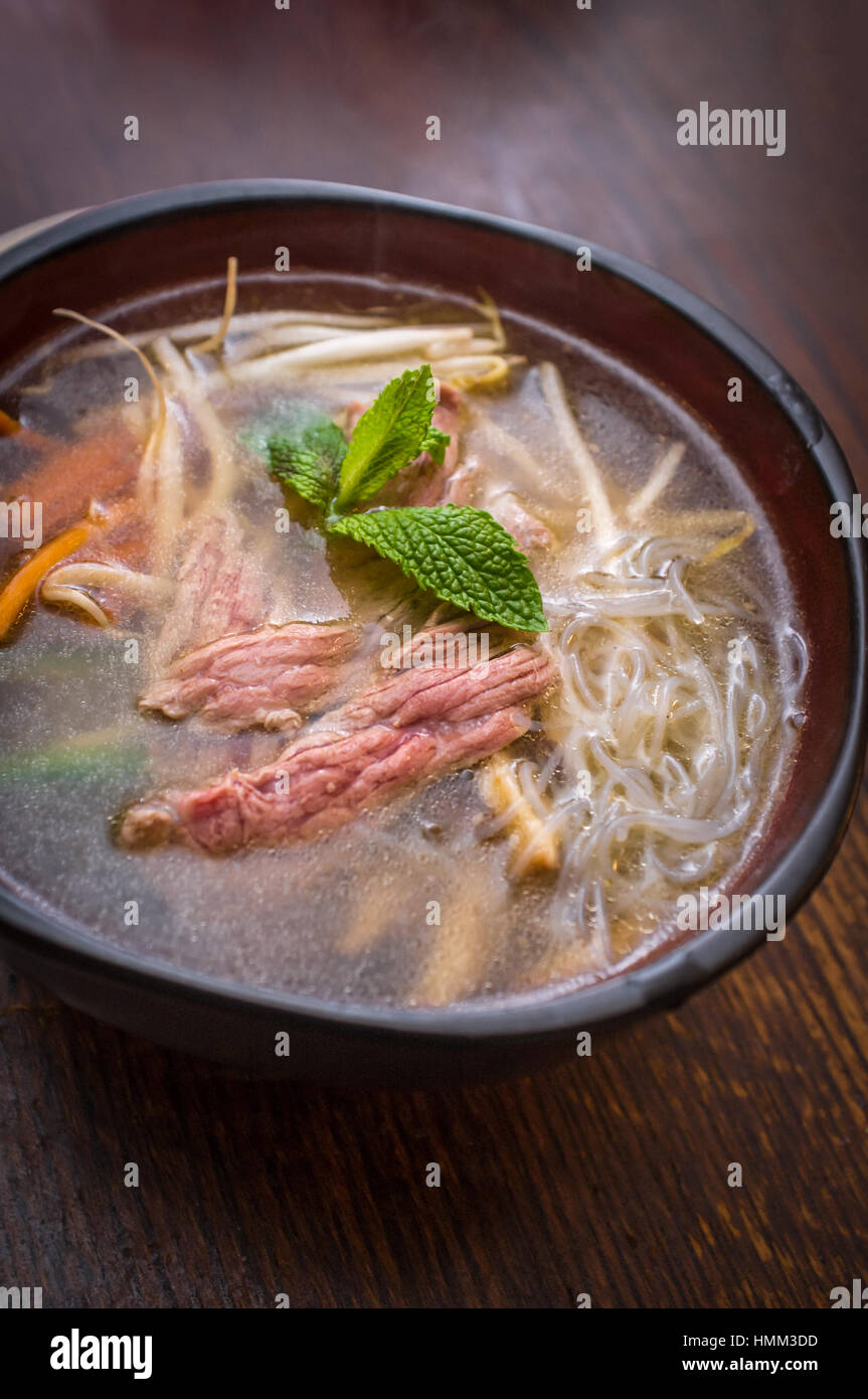 Traditional Vietnamese pho beef noodle soup garnished with mint leaves Stock Photo