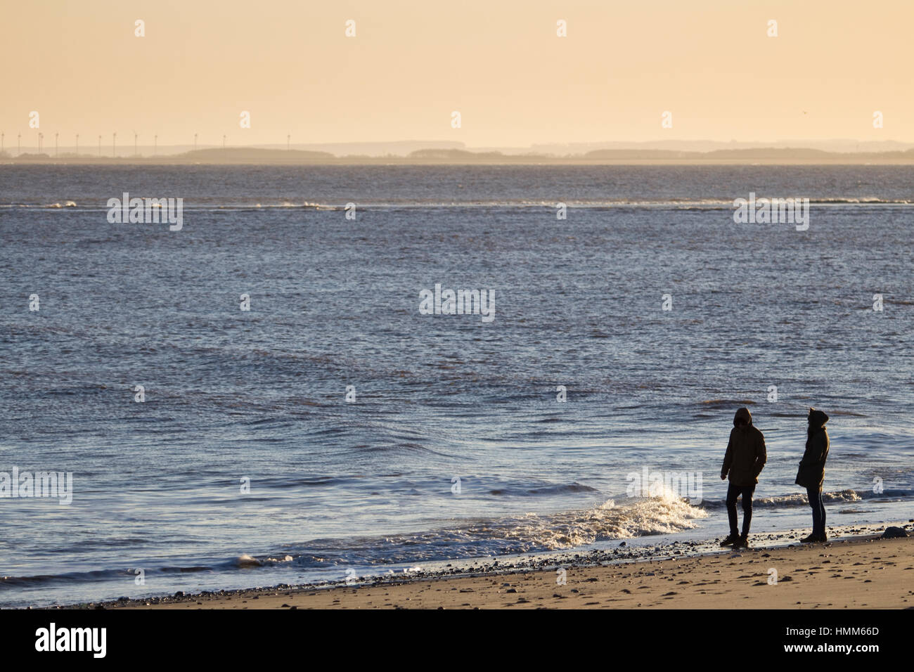 A young couple walking on a beach at dusk Stock Photo