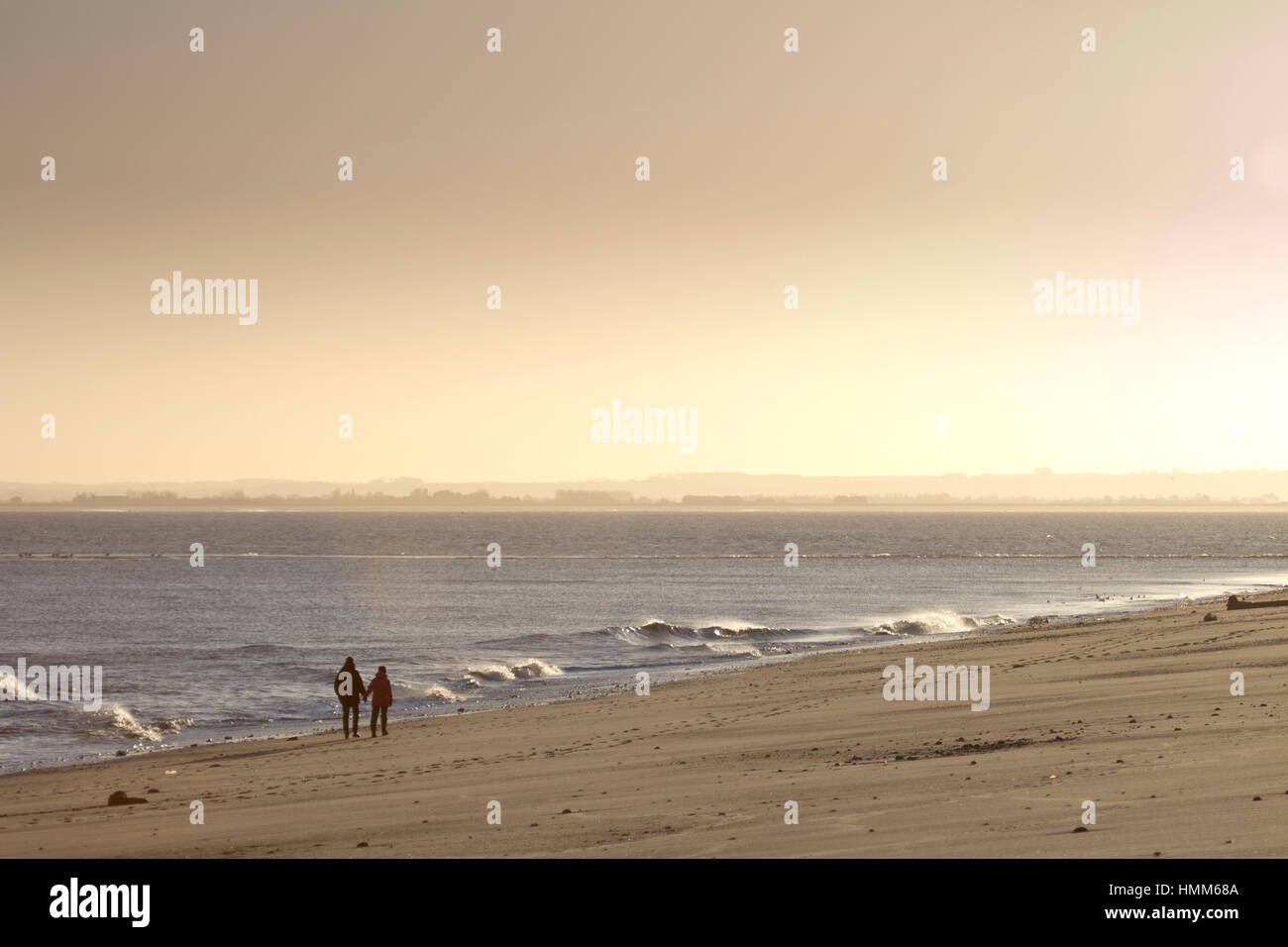 A young couple walking on a beach at dusk Stock Photo