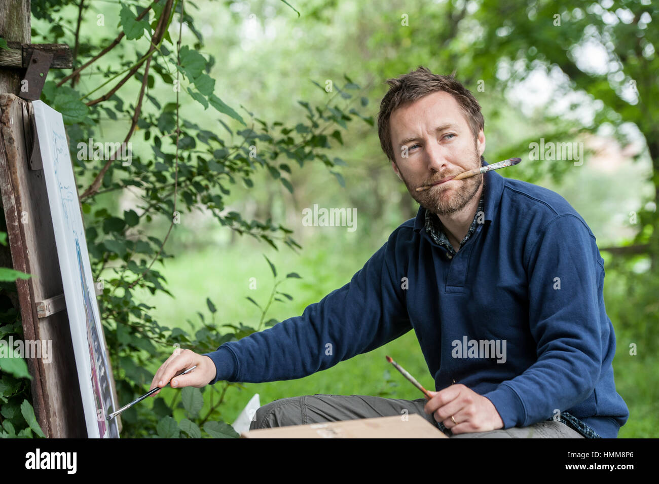 Fine artist painting. Male artist on painting on canvas in outdoor. Stock Photo