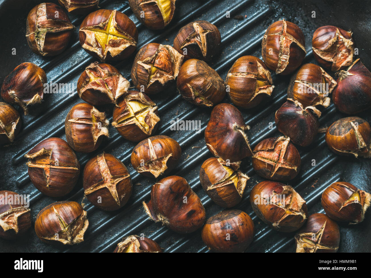 Roasted chestnuts over black cast iron grilling pan surface Stock Photo