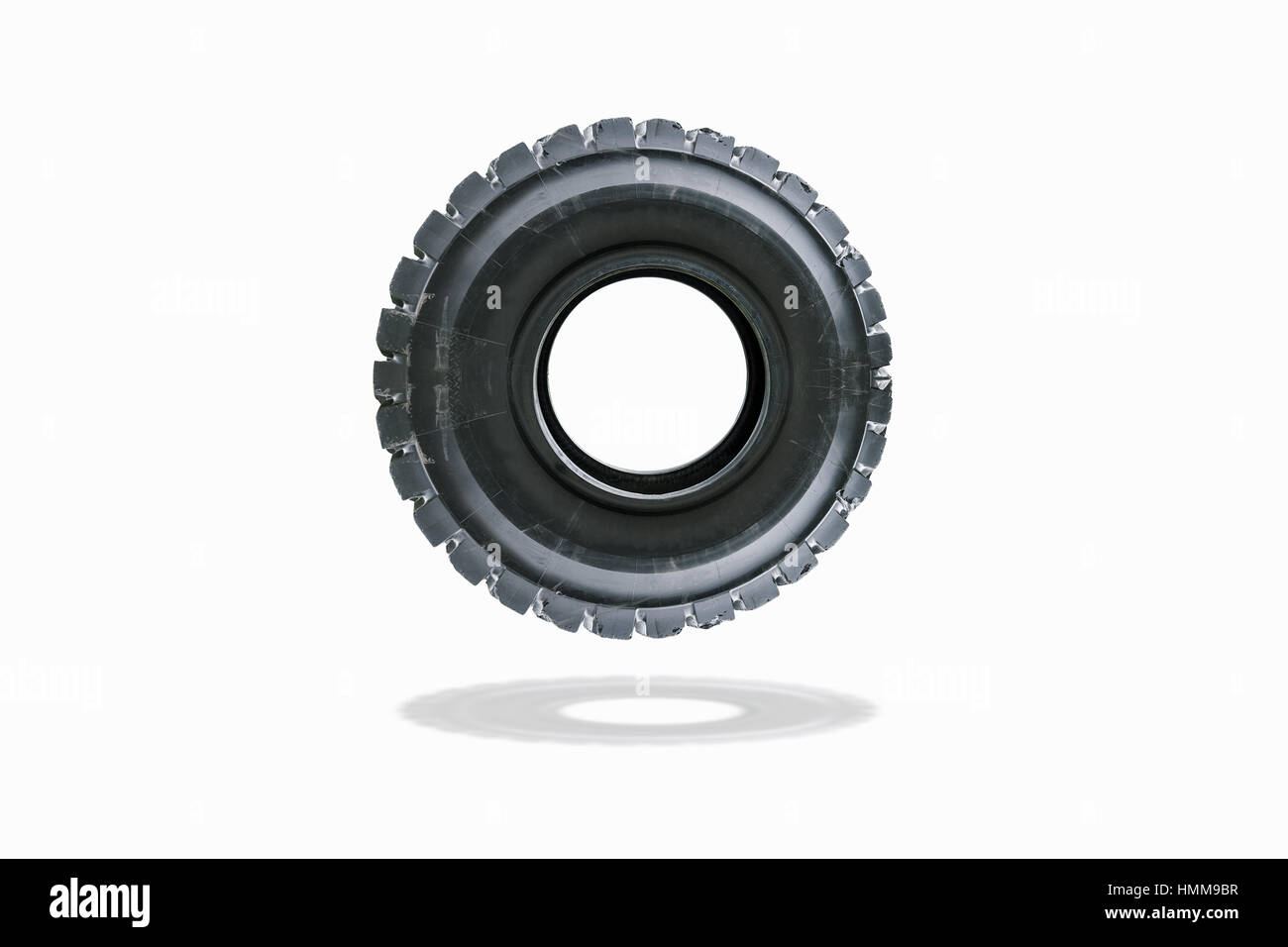 Giant tire of truck after using from heavy industrial which floating isolated on white background. Stock Photo