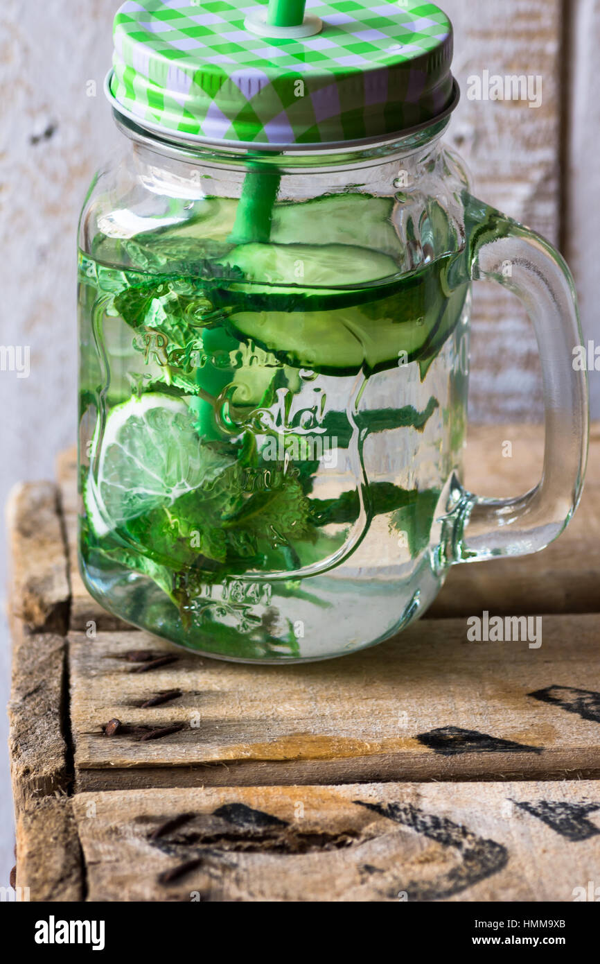 Mason jar mug with handle, lid and straw with infused detox cucumber agua  fresca water with lime and mint, on vintage plank wood, outdoors, spring  cle Stock Photo - Alamy