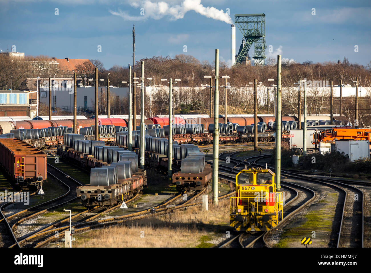 Freight station of ThyssenKrupp Stahlwerk, ThyssenKrupp Steel Europe AG steelworks, wagons with steel coils, winding tower of the former mine Thyssen  Stock Photo