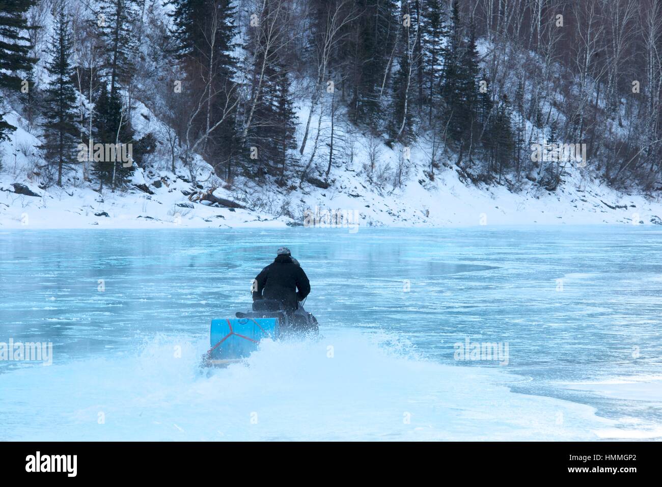 Man riding on a snowmobile frozen water Stock Photo - Alamy