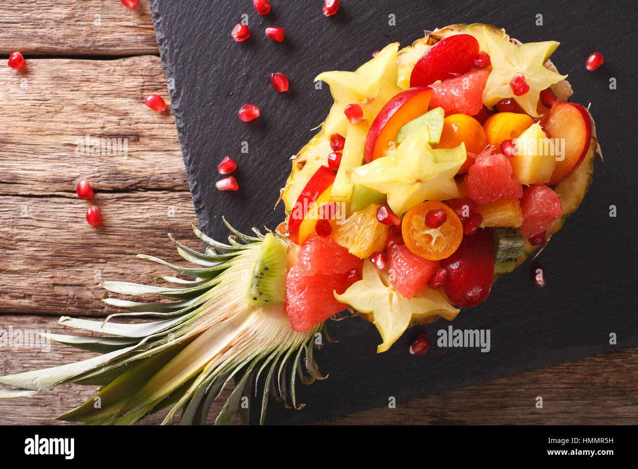 Salad of tropical fruit on a plate of pineapple close-up on the table. Horizontal view from above Stock Photo