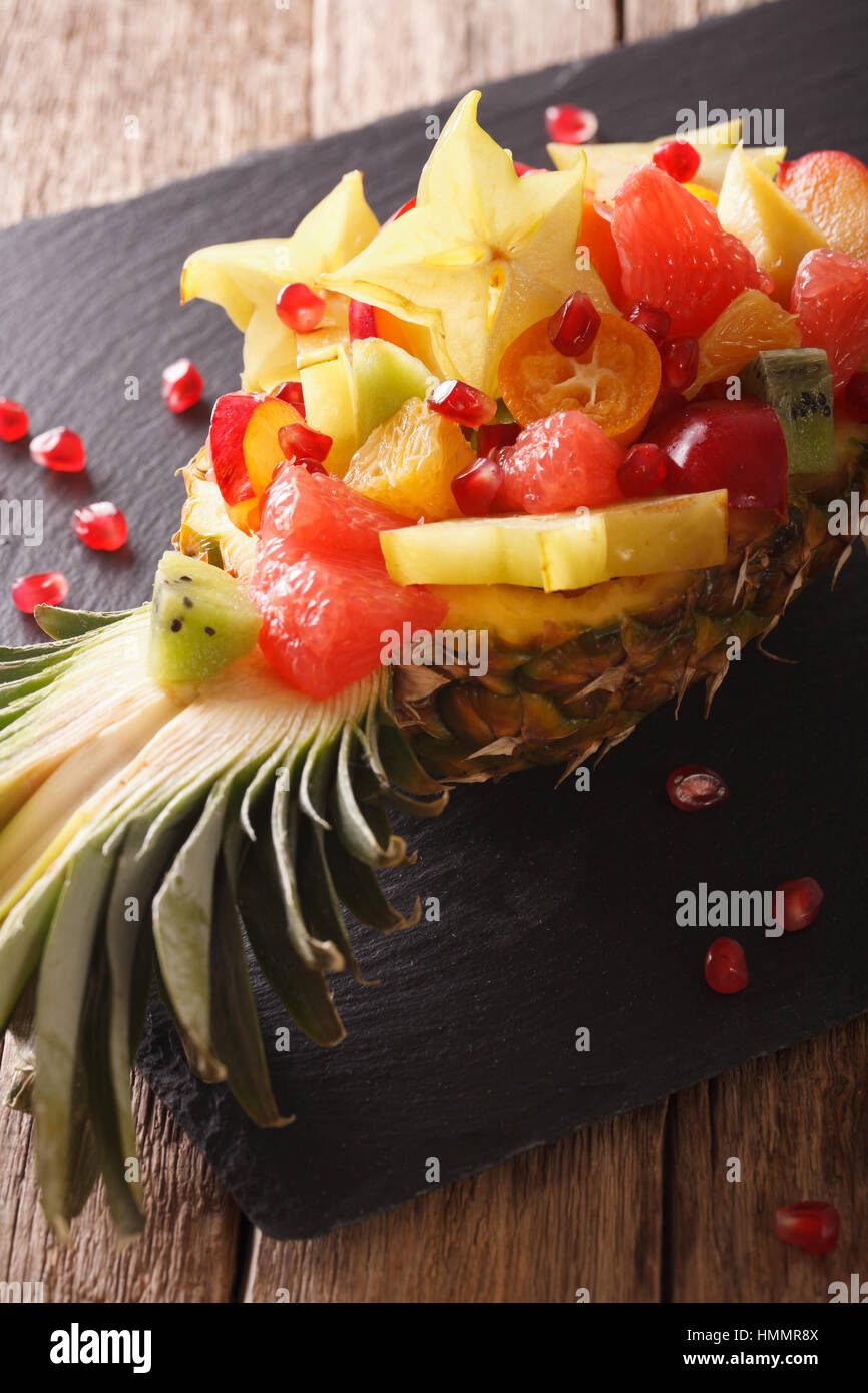 Salad of tropical fruit on a plate of pineapple close-up on the table. vertical Stock Photo