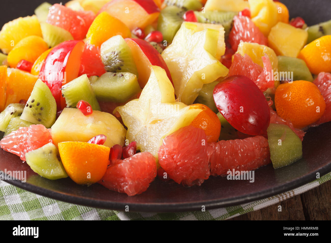 fruit salad of orange, kumquat, pineapple, carambola, grapefruit, plums and kiwi fruit macro on a plate. horizontal Stock Photo