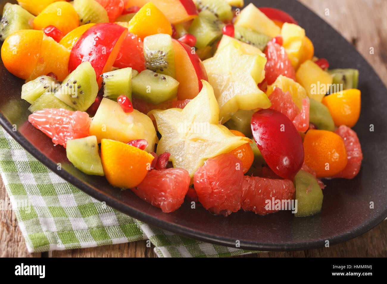 Exotic fruit salad with orange, kumquat, pineapple, carambola, grapefruit, plums and kiwi fruit close-up on a plate. horizontal Stock Photo