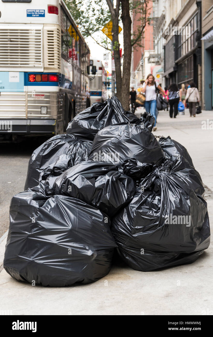 Piles of trash in black rubbish bags piled up on the pavement awaiting collection in a street in New York Stock Photo